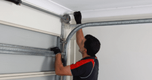 Technician repairing a garage door mechanism with tools.