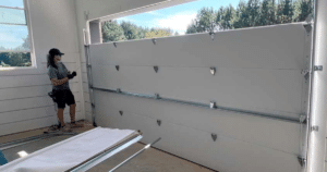 Worker installing a white garage door.